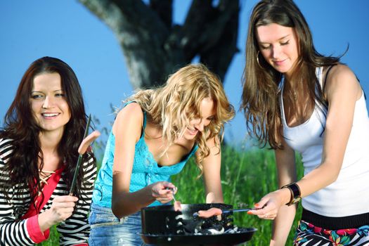 girls burn sausages on barbecue