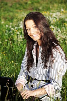 girl with laptop on green grass