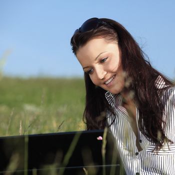 girl with laptop on green grass