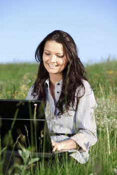 girl with laptop on green grass