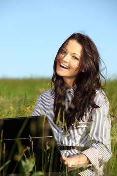 girl with laptop on green grass