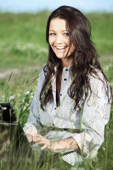 girl with laptop on green grass