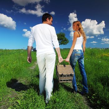 man and woman walk on picnic in green grass