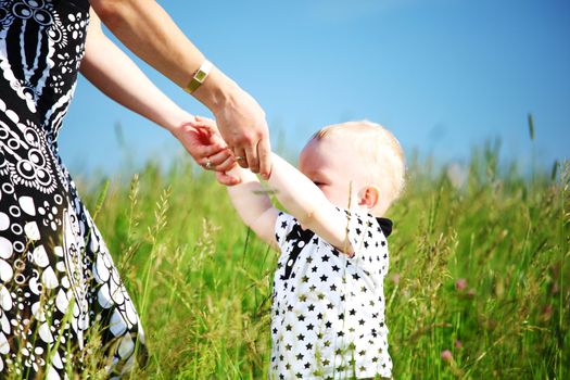 boy and mother hands in grass field
