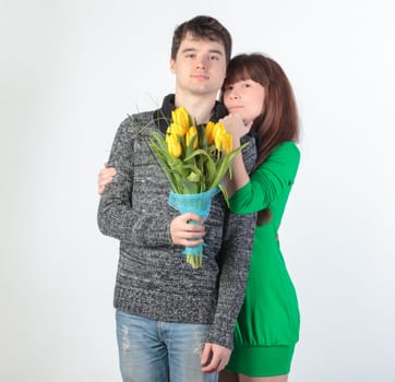 happy young couple with bouquet flowers, on gray background