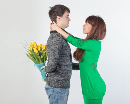 happy young couple with bouquet flowers, on gray background