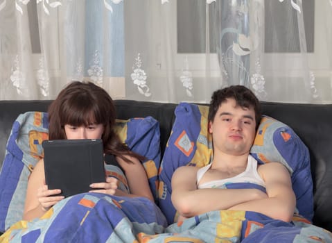 Young couple using tablet PC in their bed