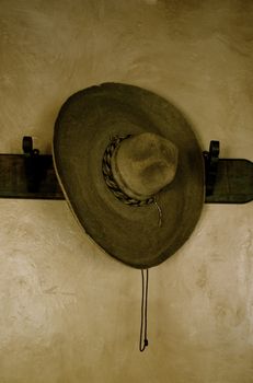An authentic, sepia sombrero hanging on a plainly plastered wall.  Emotive. Copy Space.