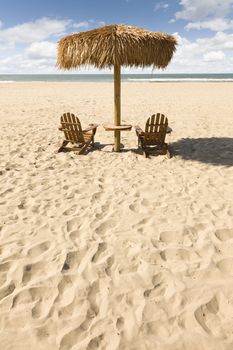 Two Beach Chairs and Umbrella on a Beautiful Ocean Front with Copy Space.