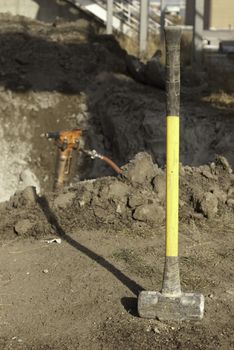 yellow sleg hammer on construction site with a jack hammer in the background