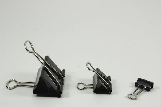 three black and silver binder clips on white background