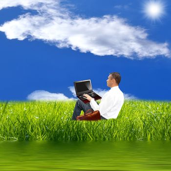 The engineer with the laptop on a green summer meadow