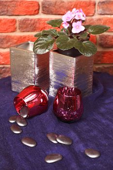 Flowers in a vase on a metal shod table against a wall from a red brick.