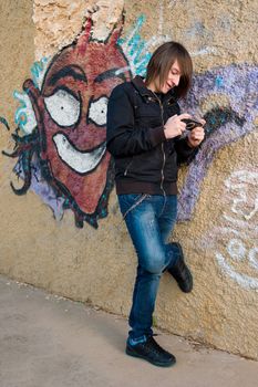 Teen playing with a console in a grunge urban setting