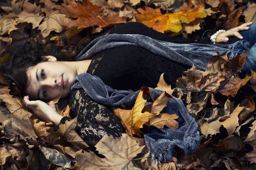 View of a beautiful girl in the middle of autumn leaves.