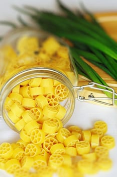 An image of bright yellow pasta in a jar and onions