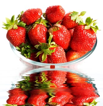 Red fresh strawberries in a glass. Reflection in water