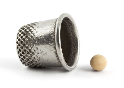 Thimble and pea isolated on white background