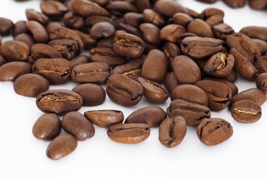 brown coffee beans scattered and isolated on a white background