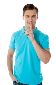 Silence gesture by a young guy wearing blue t-shirt against white background