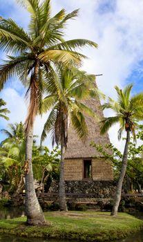 A traditional Hawaiian hut and palm trees in Polynesian Cultural Center Oahu Hawaii