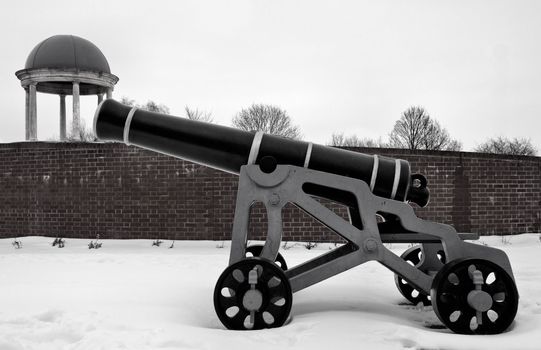 Replica cannon in snow by a wall