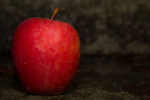 A picture of a red apple on concrete ground