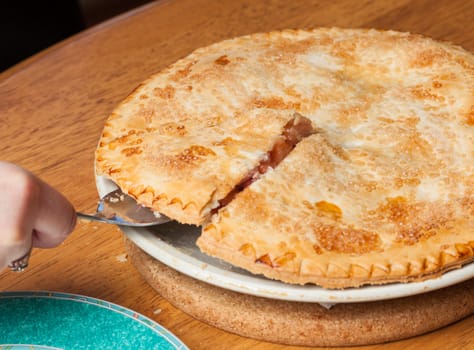 Home made baked fruit pie from oven and on table being cut with knife