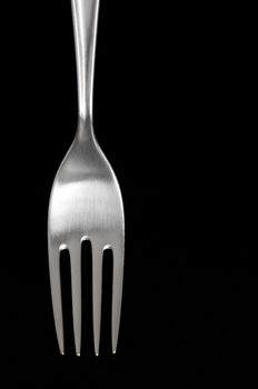 Elegant shiny silver fork from 70s, on black background.