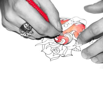 Artist drawing sketch of tattoo with red pencil