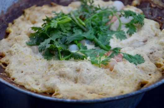 close-up egg omelet and shrimp in a frying pan