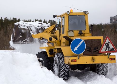 The tractor clears snow from the road blockage. Heavy special technique. 