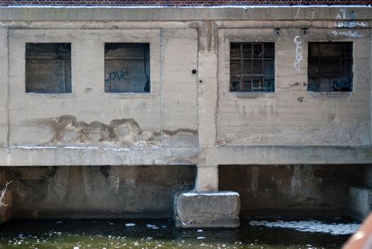 An abandoned and decaying mill sits on the river alone