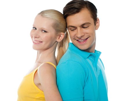 Young couple smiling and posing back to back in front of camera