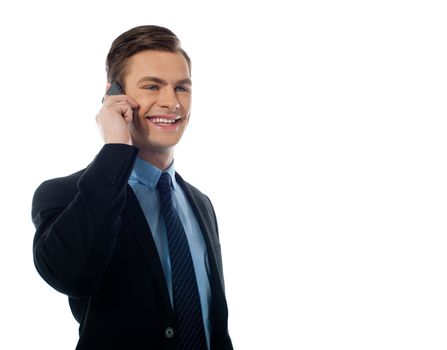 Handsome business executive communicating on cellphone against white background