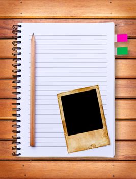 notebook and vintage photo frame on wood background