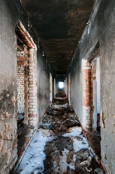 Corridor in abandoned house with trash and broken walls