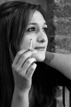 Pretty and elegant girl smoking small cigarette in black and white