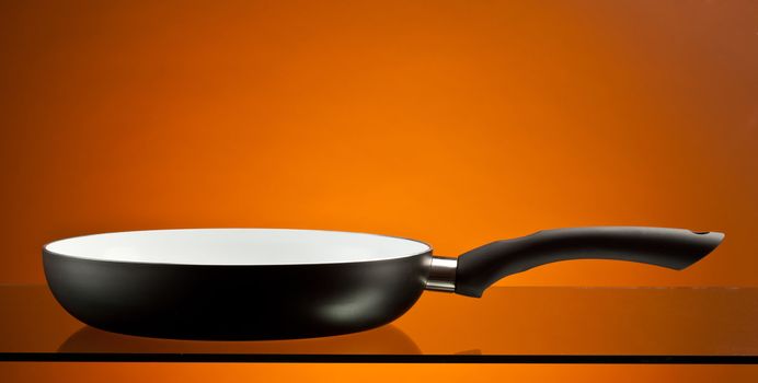 new ceramic frying pan over orange background