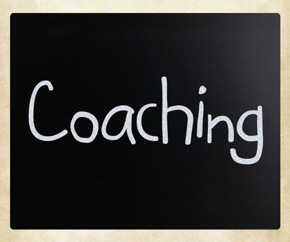 "Coaching" handwritten with white chalk on a blackboard