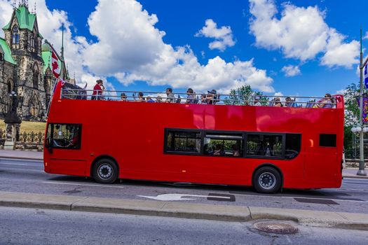  A red bus with tourists beside Parliament building on Parliament hill in Ottawa, Ontario, Canada