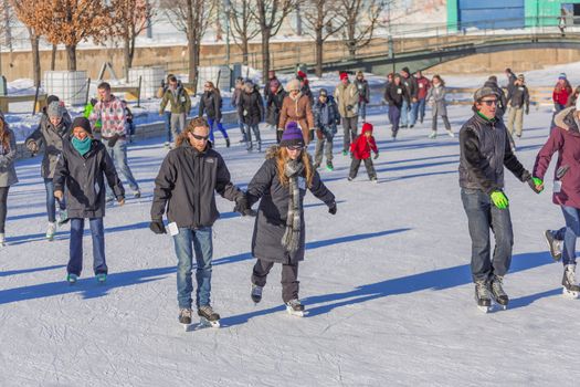 A couple skating, the woman is teaching her man how to skate perfectly in a cold winter day in the beautiful Skating Rink in Old Port of Montreal, Quebec ,Canada