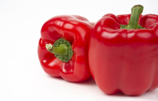 Bright Red Vegetable Peppers Sit in a Pair on a WHite Background
