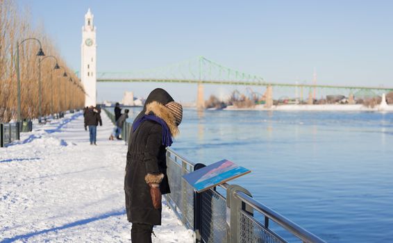 Two people are looking on a map, beside Saint Lawrence river, to find their way through the city of Montreal in Quebec, Canada