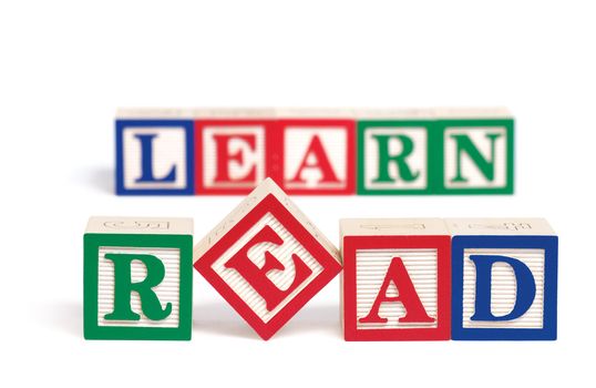 Alphabet blocks spelling the word, "read." Behind them and slightly out of focus are alphabet blocks spelling the word, "learn." Isolated on white.