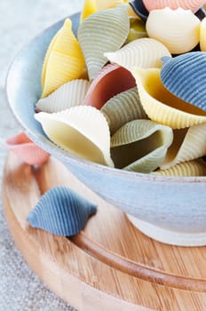 Pasta in bowl on a wooden board close up