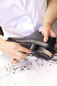 A craftsmwoman in his shop repairing footwear