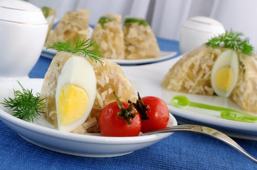 A piece of jellied chicken with egg and pickled cherry