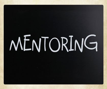 "Mentoring" handwritten with white chalk on a blackboard