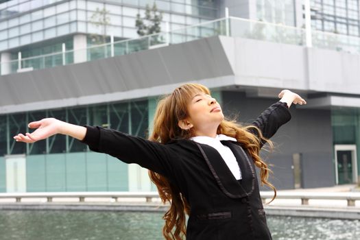 Woman relaxing with arms open enjoying her freedom and office building background